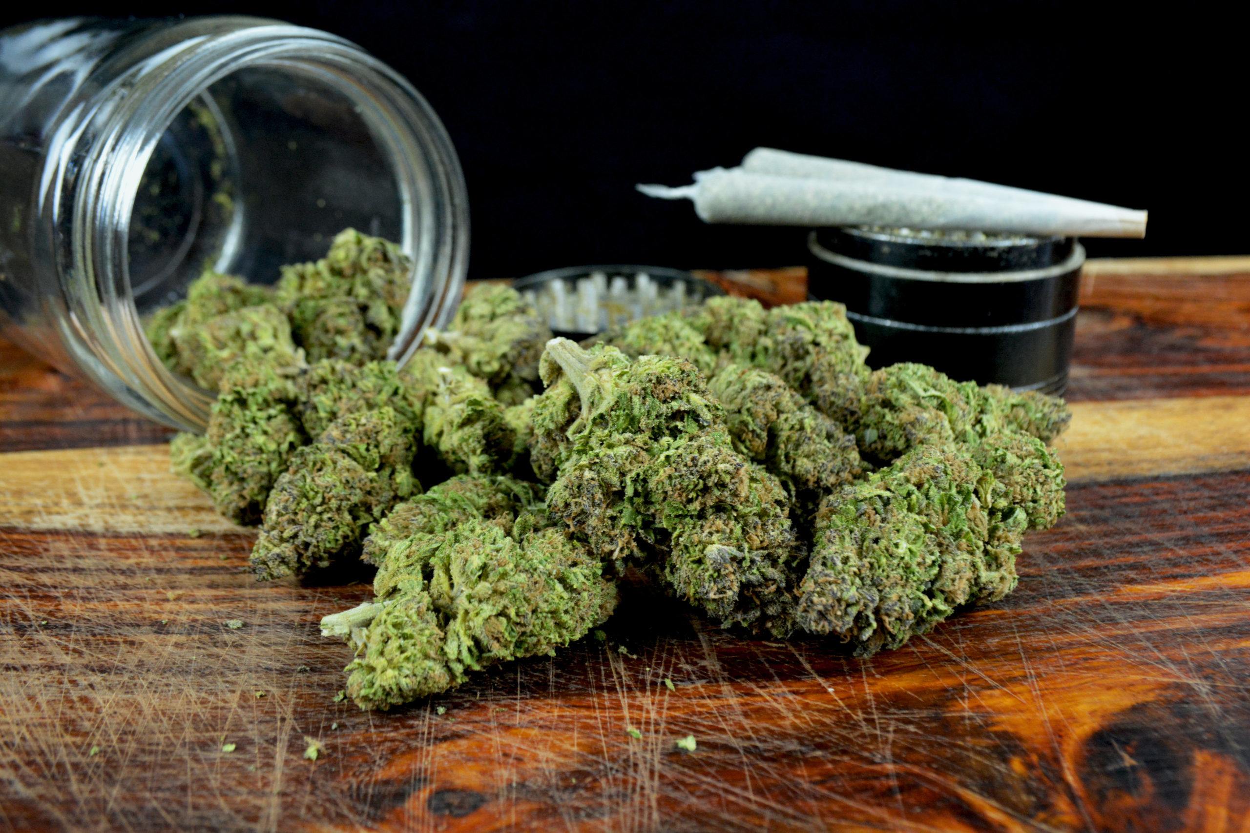 One ounce marijuana with jar, joints and grinder against black background One ounce marijuana with jar, joints and grinder against black background