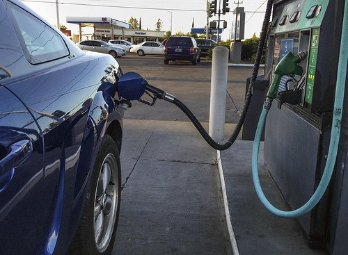 gas pump filling up a back sedan at a gas station