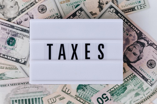 US dollar bills with a white block spelling 'taxes'